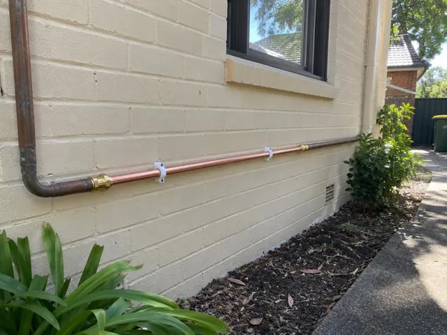 Exterior cream brick wall with a copper water pipe repaired along the side of a house in Macquarie Park